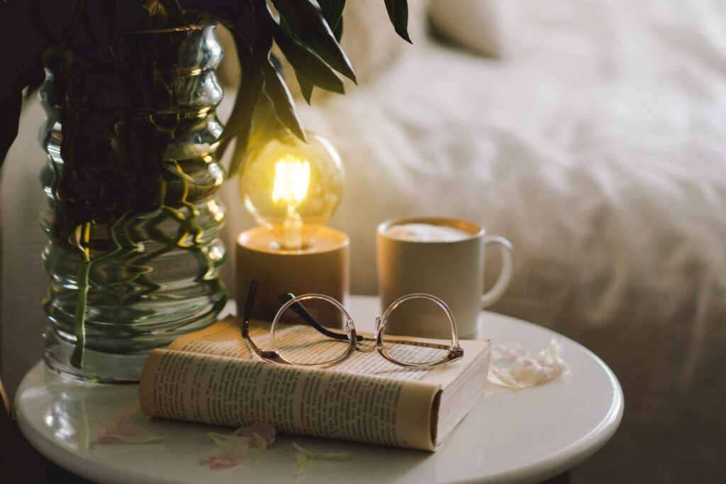 Open book with glasses, cup coffee and bouquet white pink peonies flowers. Read and rest. Cozy home