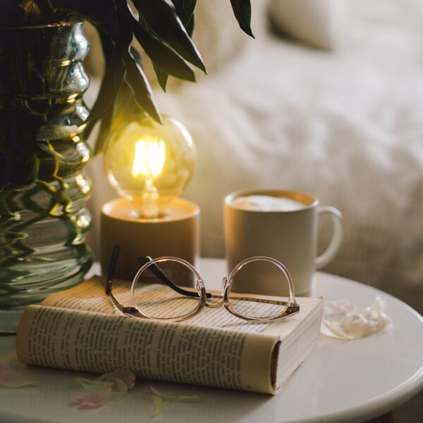 Open book with glasses, cup coffee and bouquet white pink peonies flowers. Read and rest. Cozy home